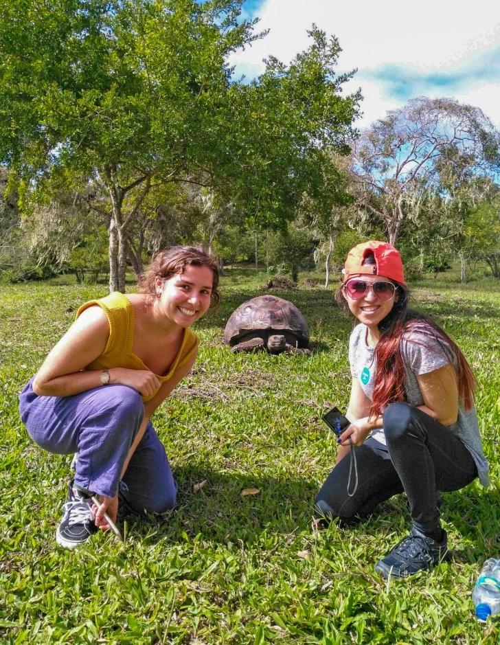 students in ecuador pose with a giant tortoise